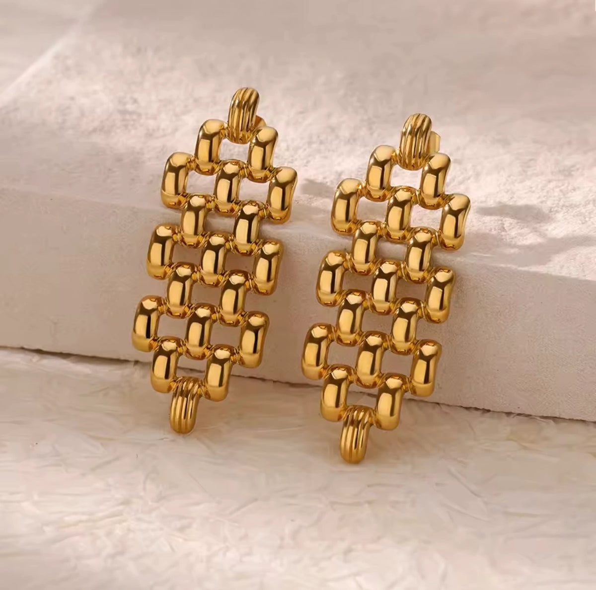 Gold geometric earrings on a light marble background