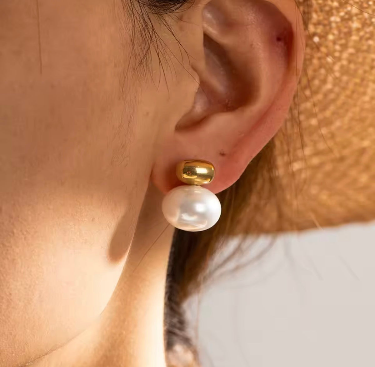 Pearl earring with gold accent worn by a person