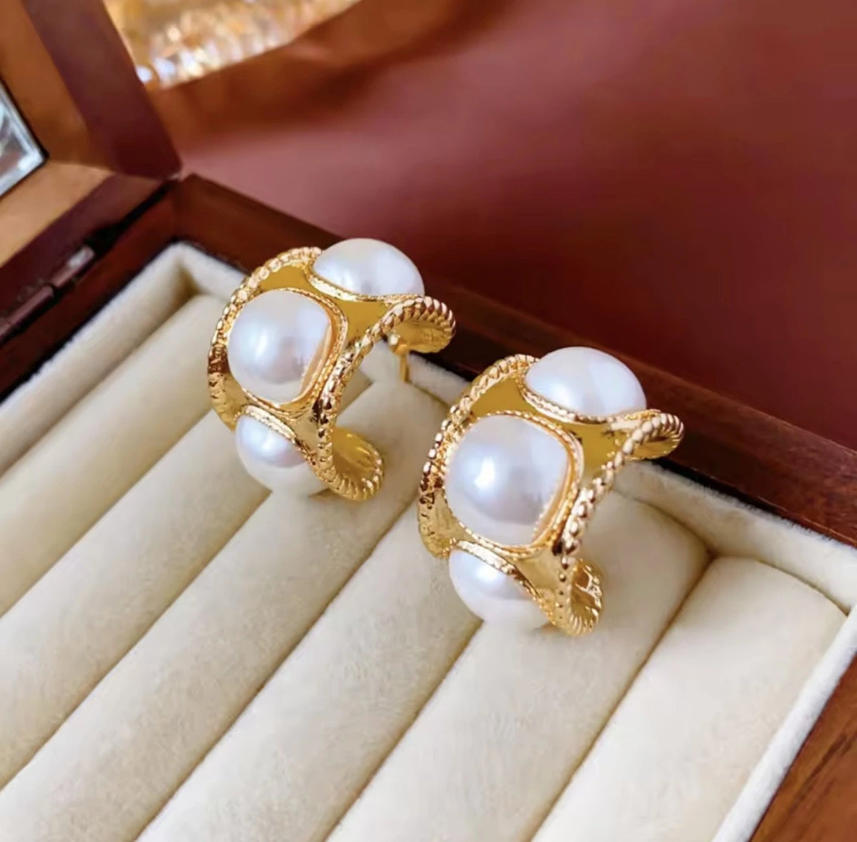 Gold earrings with pearls on a beige jewelry display