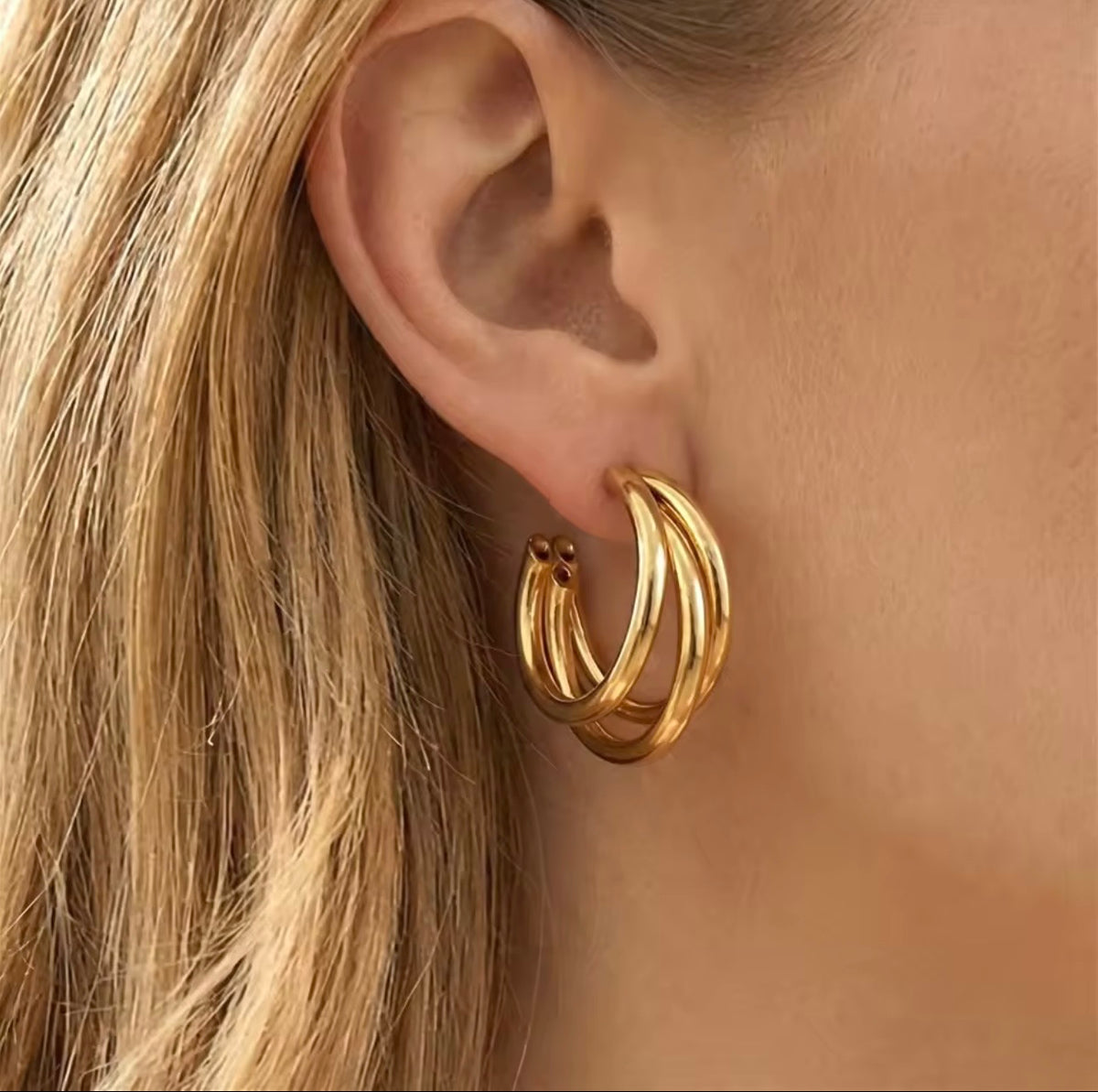 Gold hoop earrings worn by a person with blonde hair.