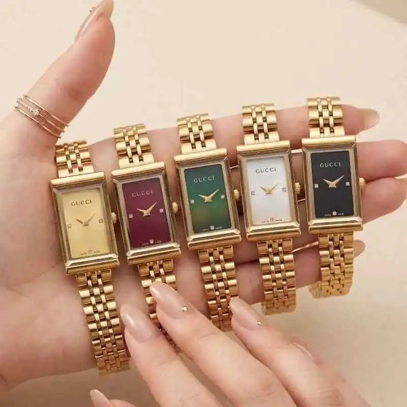 A close-up of a Gucci women's watch with a gold-tone rectangular case and link bracelet, featuring a green dial with diamond hour markers, worn on a wrist.