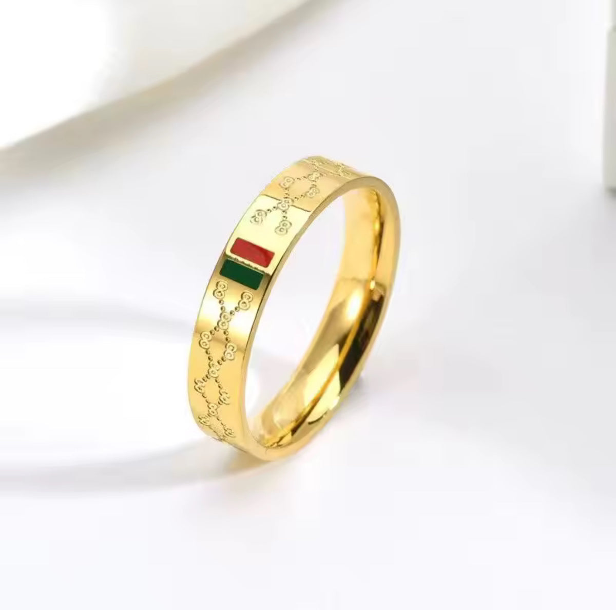 Gold ring with a red and green accent on a white background