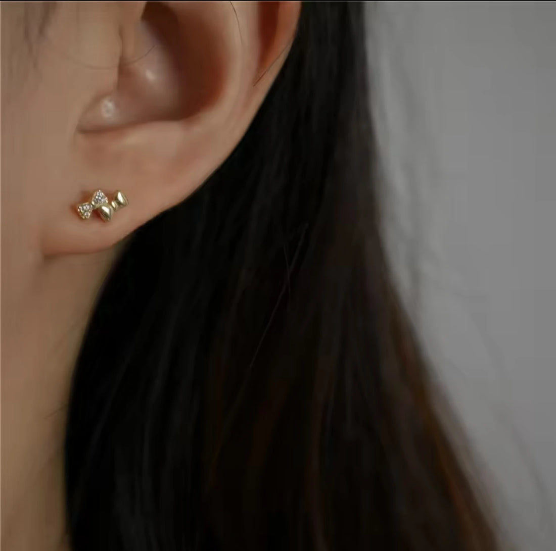 Close-up of an ear wearing a gold earring with a blurred background