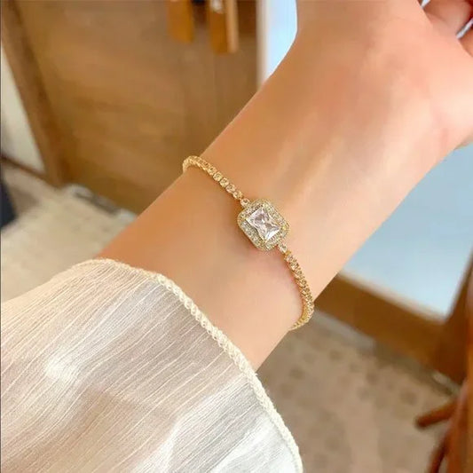 Elegant gold tennis bracelet with emerald cut center stone